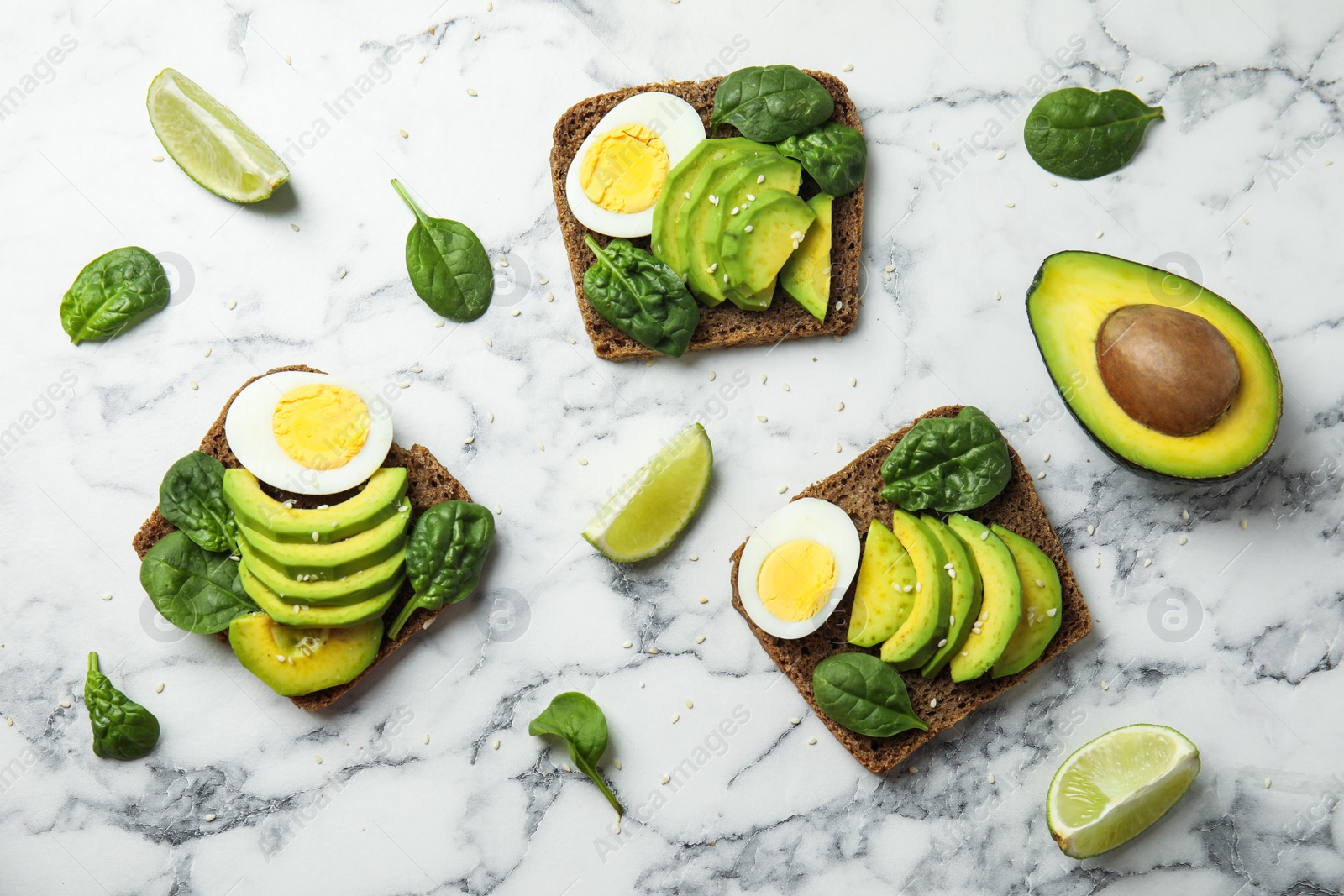 Photo of Flat lay composition with avocado toasts on white marble table