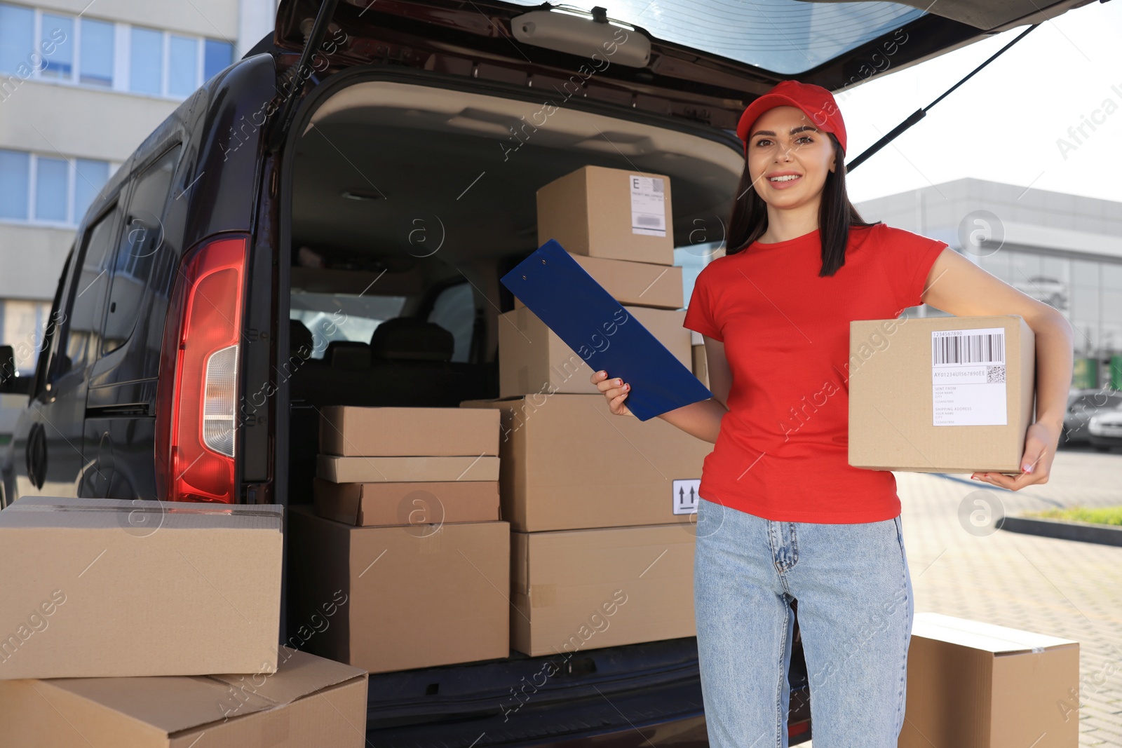 Photo of Courier with parcel and clipboard near delivery van outdoors