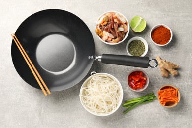 Photo of Flat lay composition with black wok, spices and products on grey textured table