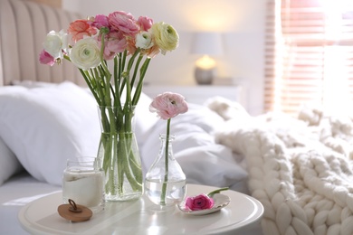 Photo of Beautiful ranunculus flowers on table in bedroom, space for text