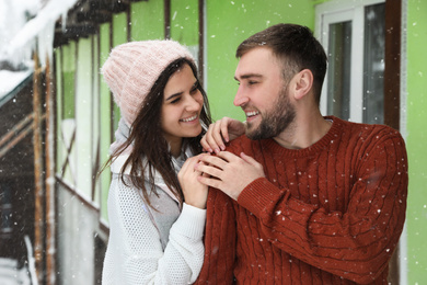 Lovely couple wearing warm sweaters outdoors on snowy day. Winter season