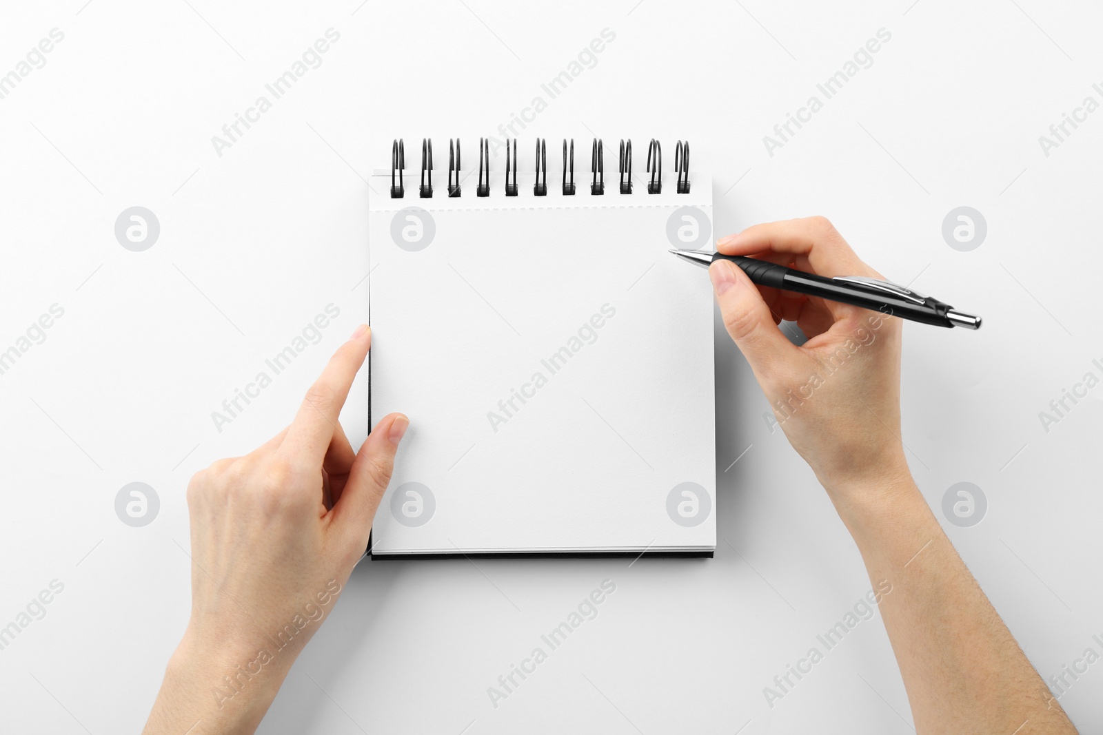 Photo of Woman writing in notebook on white background, top view