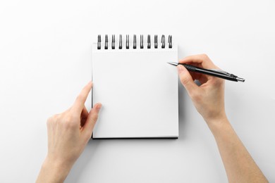 Photo of Woman writing in notebook on white background, top view