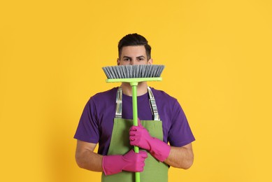 Man with green broom on orange background