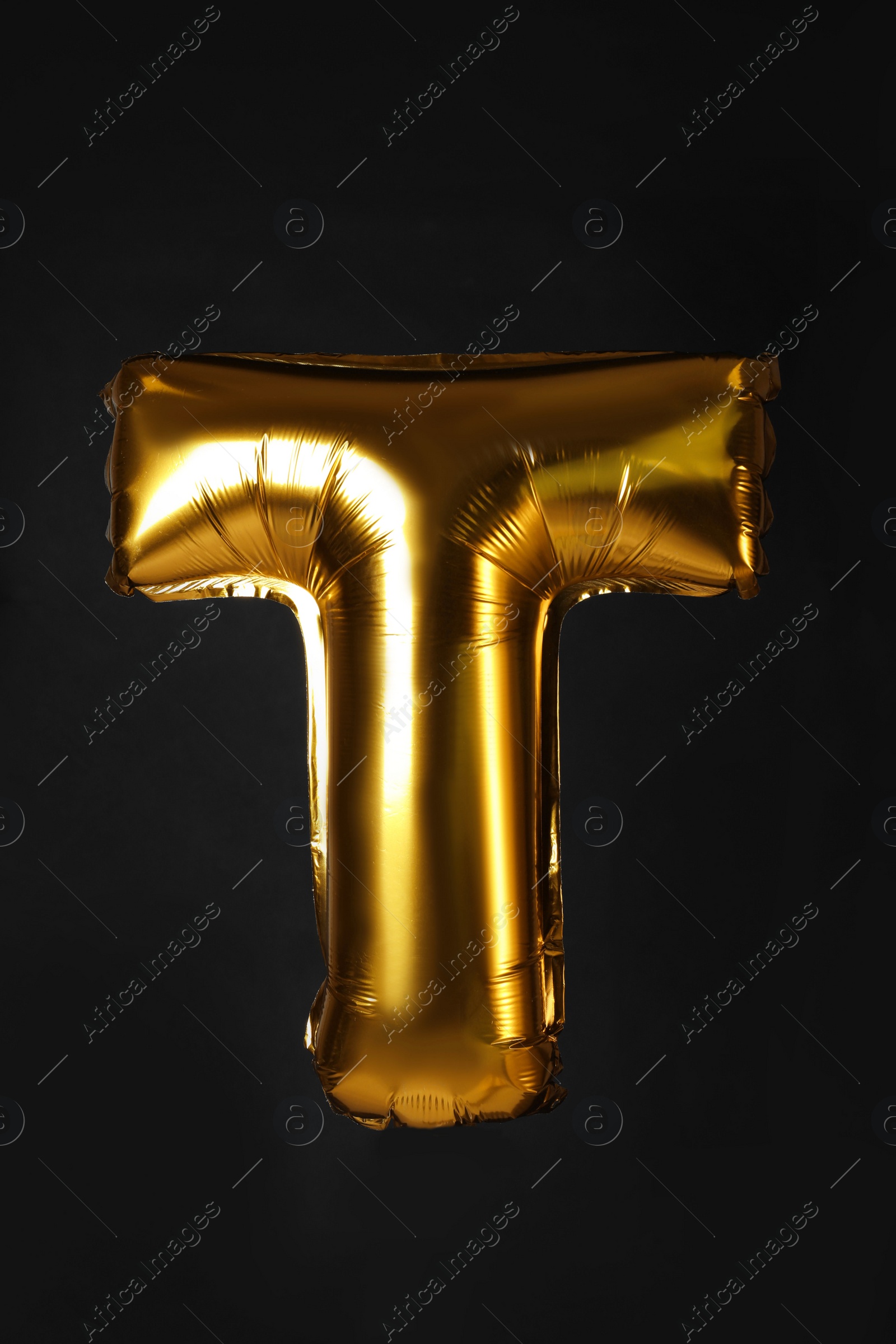 Photo of Golden letter T balloon on black background