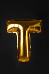 Golden letter T balloon on black background