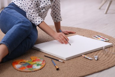 Photo of Woman artist drawing picture on canvas indoors, closeup