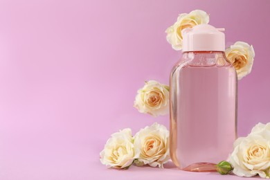 Photo of Bottle of micellar water and beautiful roses on light pink background. Space for text