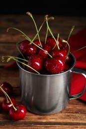 Photo of Wet red cherries in enameled mug on wooden table