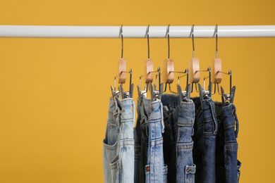 Rack with different jeans on yellow background