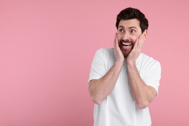 Photo of Portrait of happy surprised man on pink background, space for text