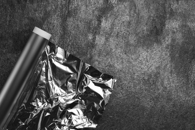 Roll of aluminum foil on grey table, top view. Space for text