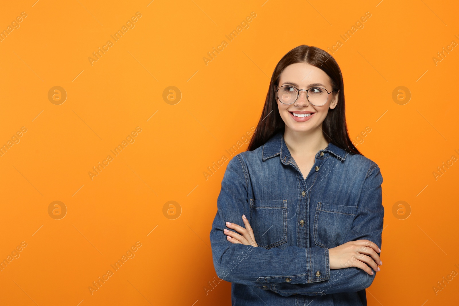 Photo of Smiling woman in stylish eyeglasses on orange background. Space for text