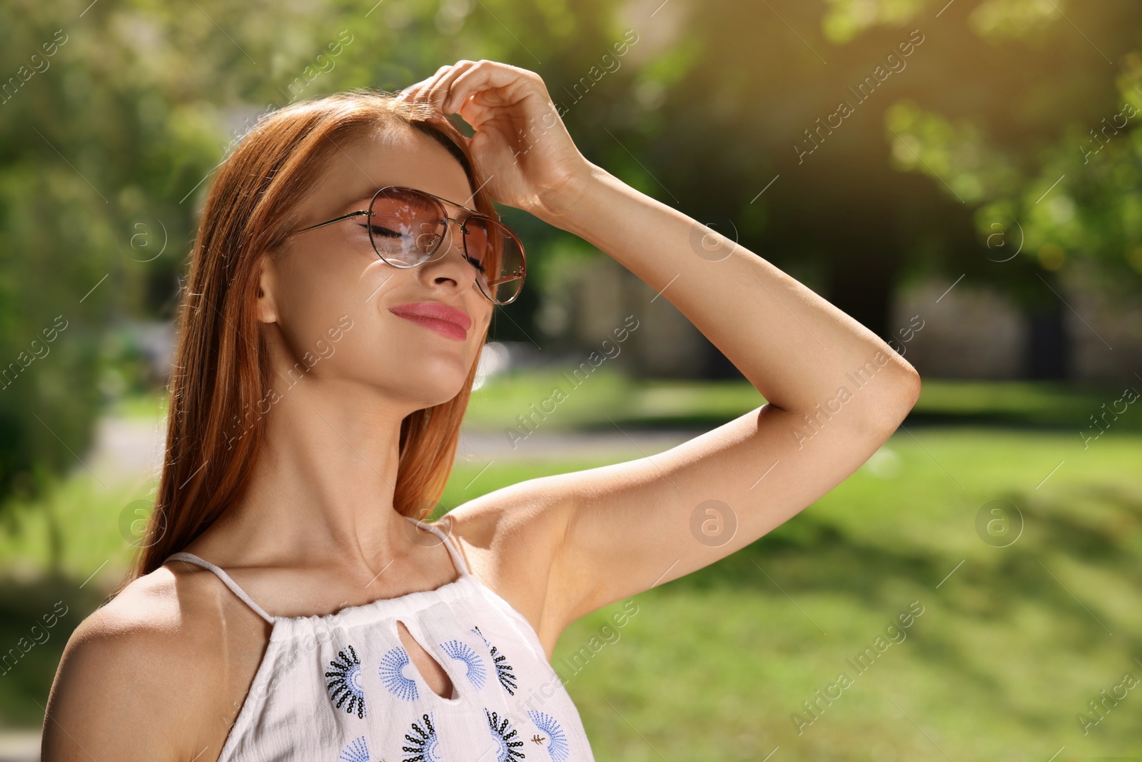Photo of Beautiful woman wearing sunglasses in park, space for text