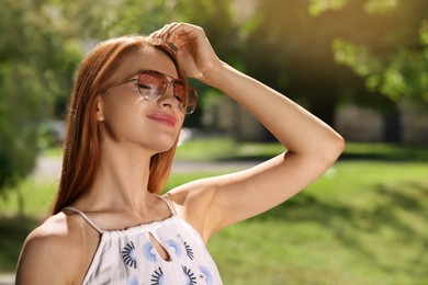 Photo of Beautiful woman wearing sunglasses in park, space for text