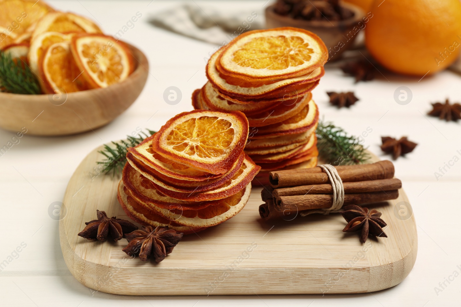 Photo of Dry orange slices, anise stars and cinnamon sticks on white table