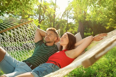 Photo of Young couple resting in comfortable hammock at green garden