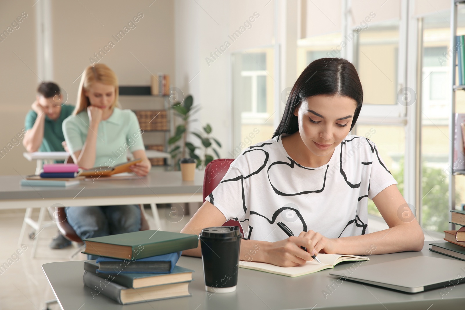 Photo of Young woman studying at table in library
