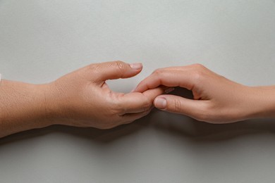 Photo of Woman holding hands with her mother light grey background, top view