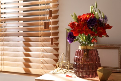 Photo of Vase with beautiful flowers on wooden table in room, space for text