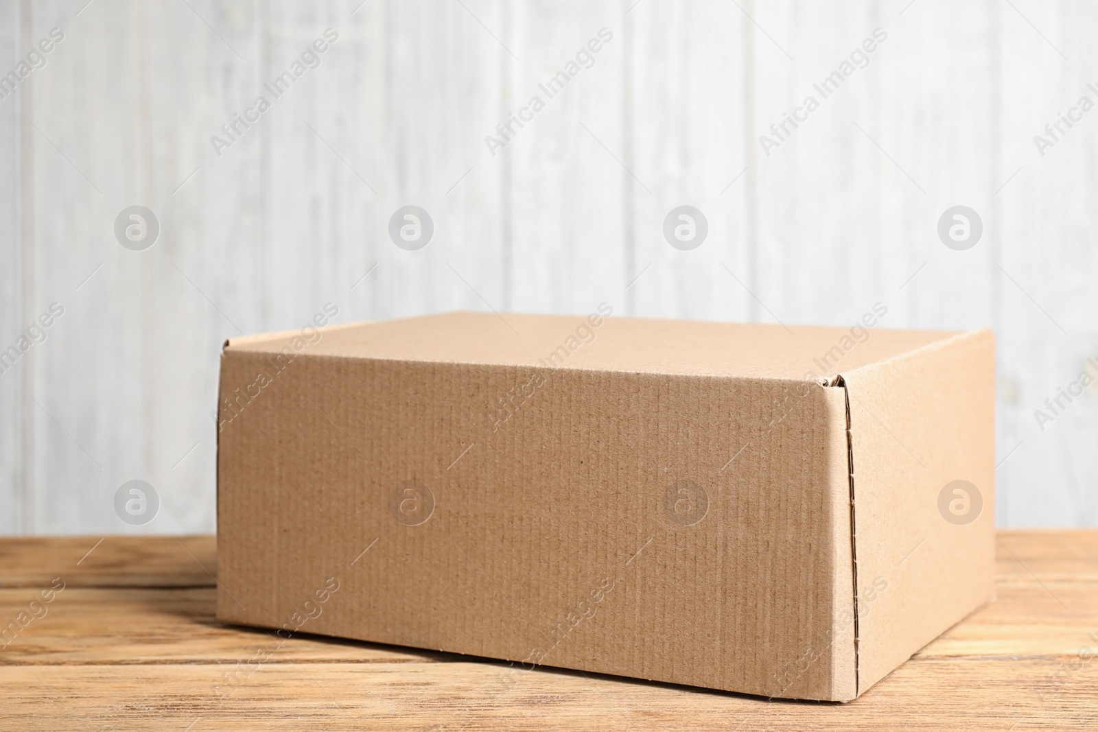 Photo of Cardboard box on wooden table against white background