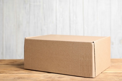 Photo of Cardboard box on wooden table against white background