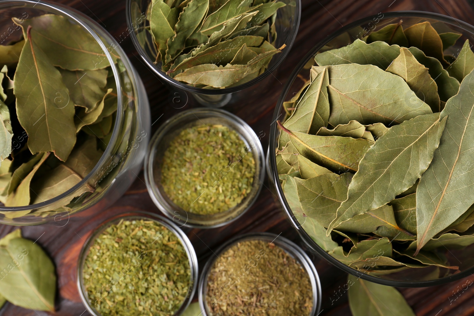 Photo of Whole and ground bay leaves on wooden table, flat lay