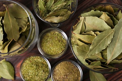 Photo of Whole and ground bay leaves on wooden table, flat lay