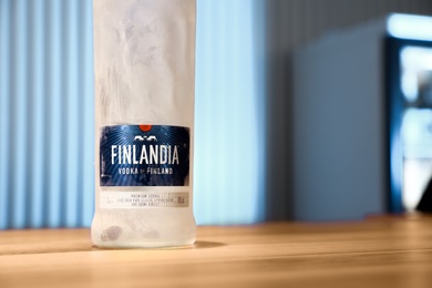 Photo of MYKOLAIV, UKRAINE - SEPTEMBER 23, 2019: Bottle of Finlandia vodka on wooden bar counter. Space for text