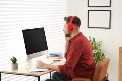 Photo of Man in headphones studying on computer at home. Online translation course