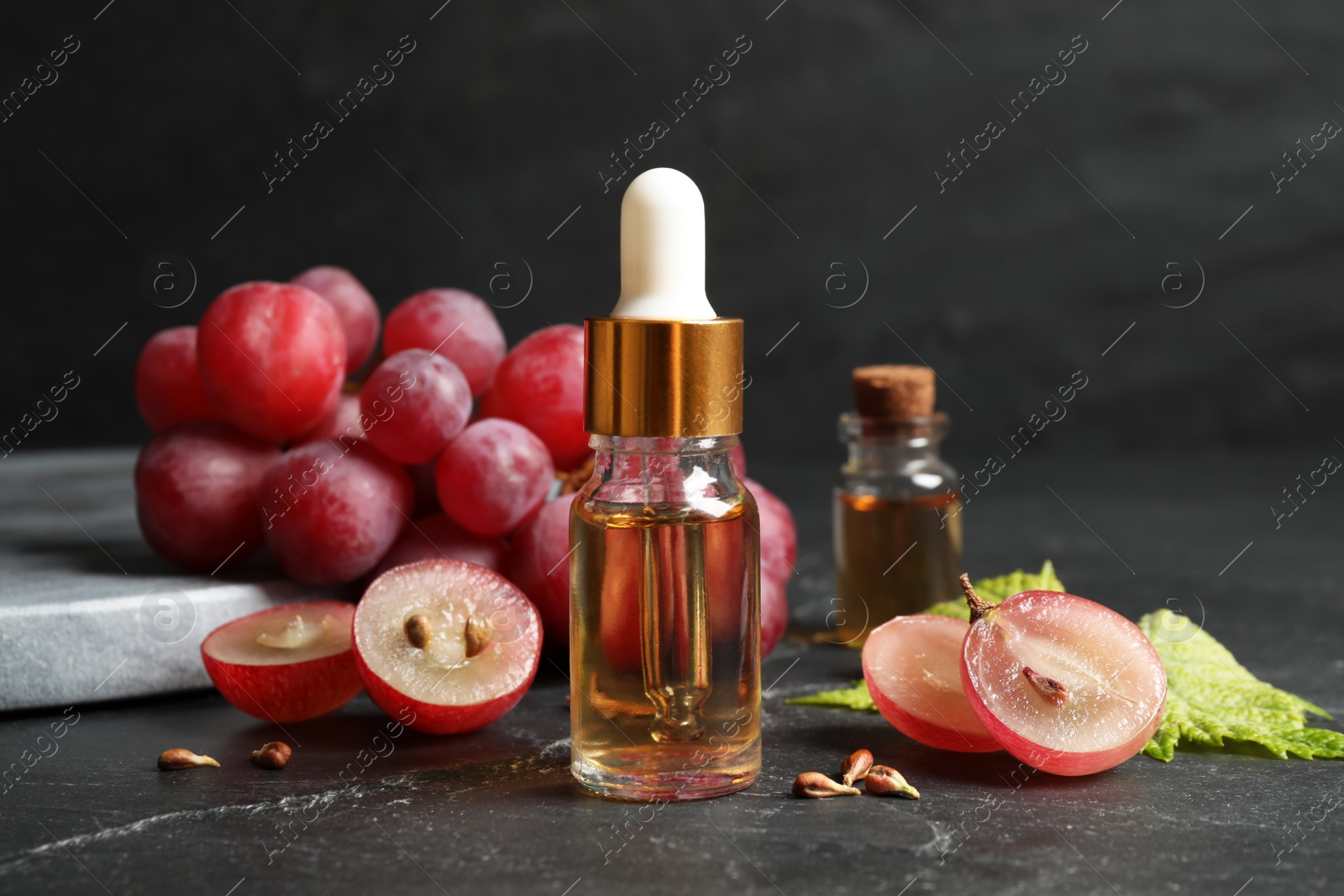 Photo of Bottle of natural grape seed oil on dark table. Organic cosmetic