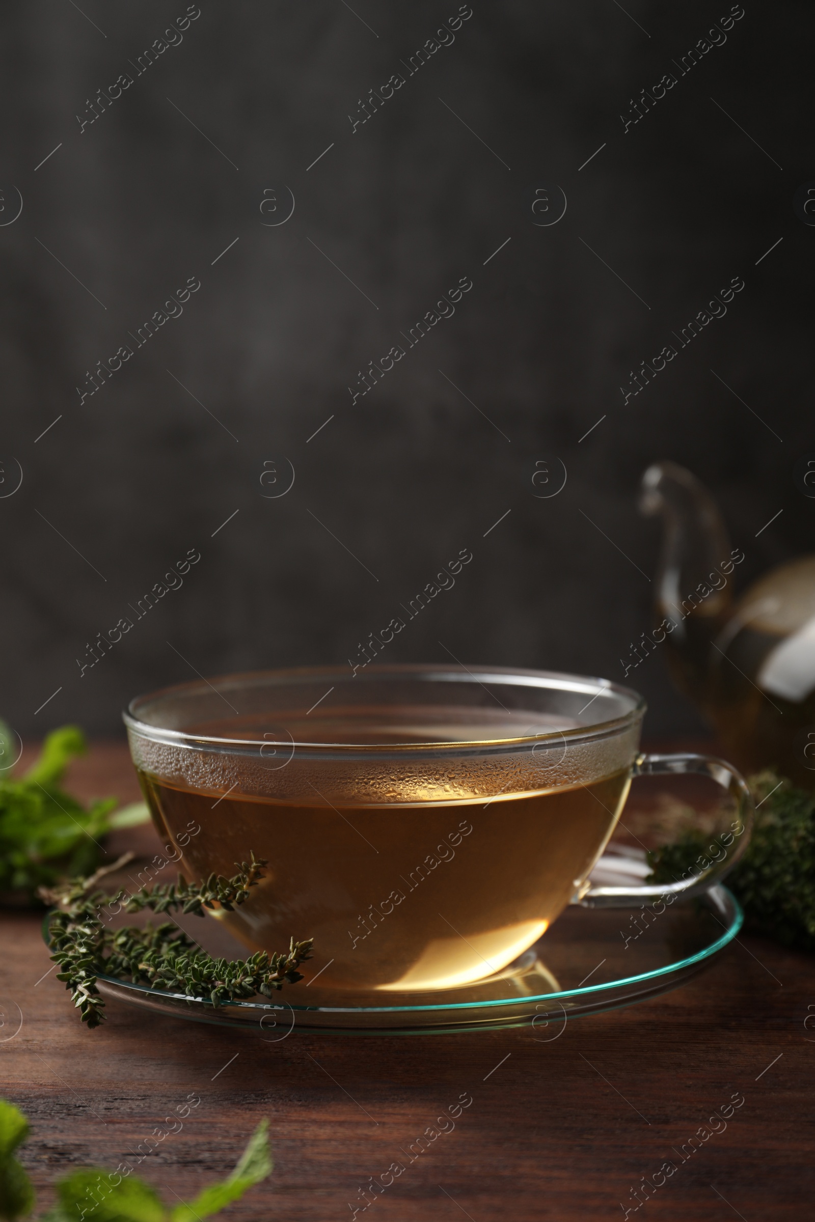 Photo of Cup of aromatic herbal tea and fresh thyme on wooden table