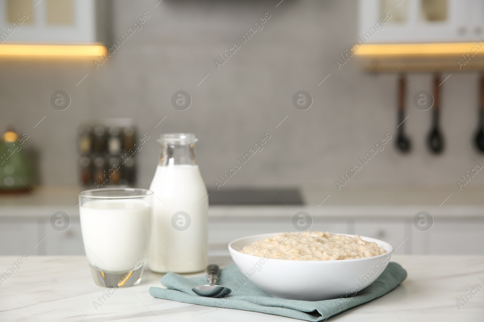 Photo of Breakfast time. Tasty oatmeal in bowl and milk on white marble table. Space for text