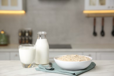 Photo of Breakfast time. Tasty oatmeal in bowl and milk on white marble table. Space for text