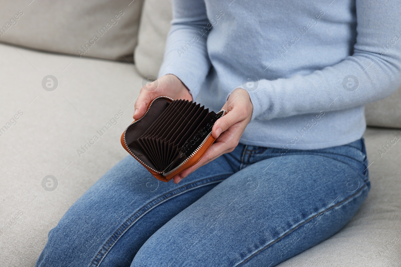 Photo of Woman with empty wallet on sofa indoors, closeup