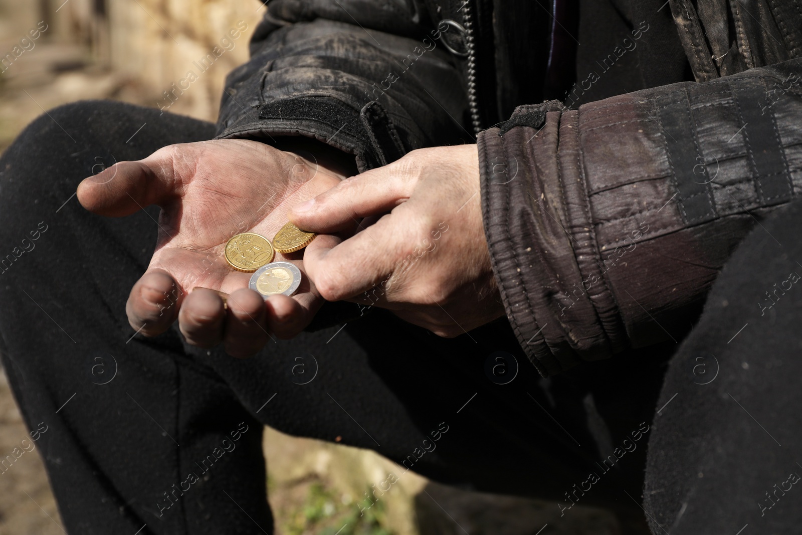 Photo of Poor homeless man holding coins outdoors, closeup