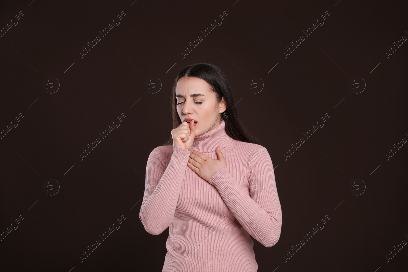 Photo of Young woman coughing on dark background. Cold symptoms