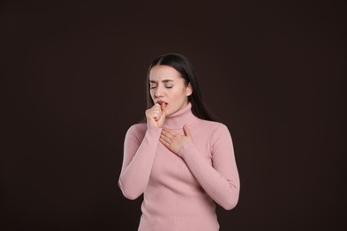 Young woman coughing on dark background. Cold symptoms