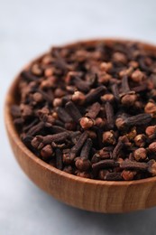 Photo of Aromatic cloves in bowl on gray table, closeup