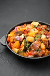 Photo of Dish with tasty ratatouille on black table, closeup