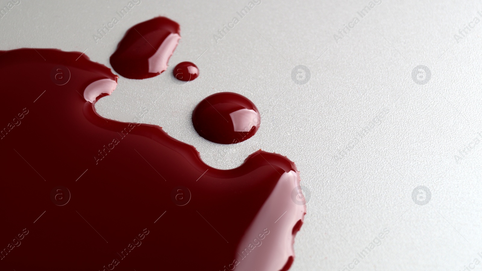 Photo of Stain and drops of blood on light grey background, closeup. Space for text