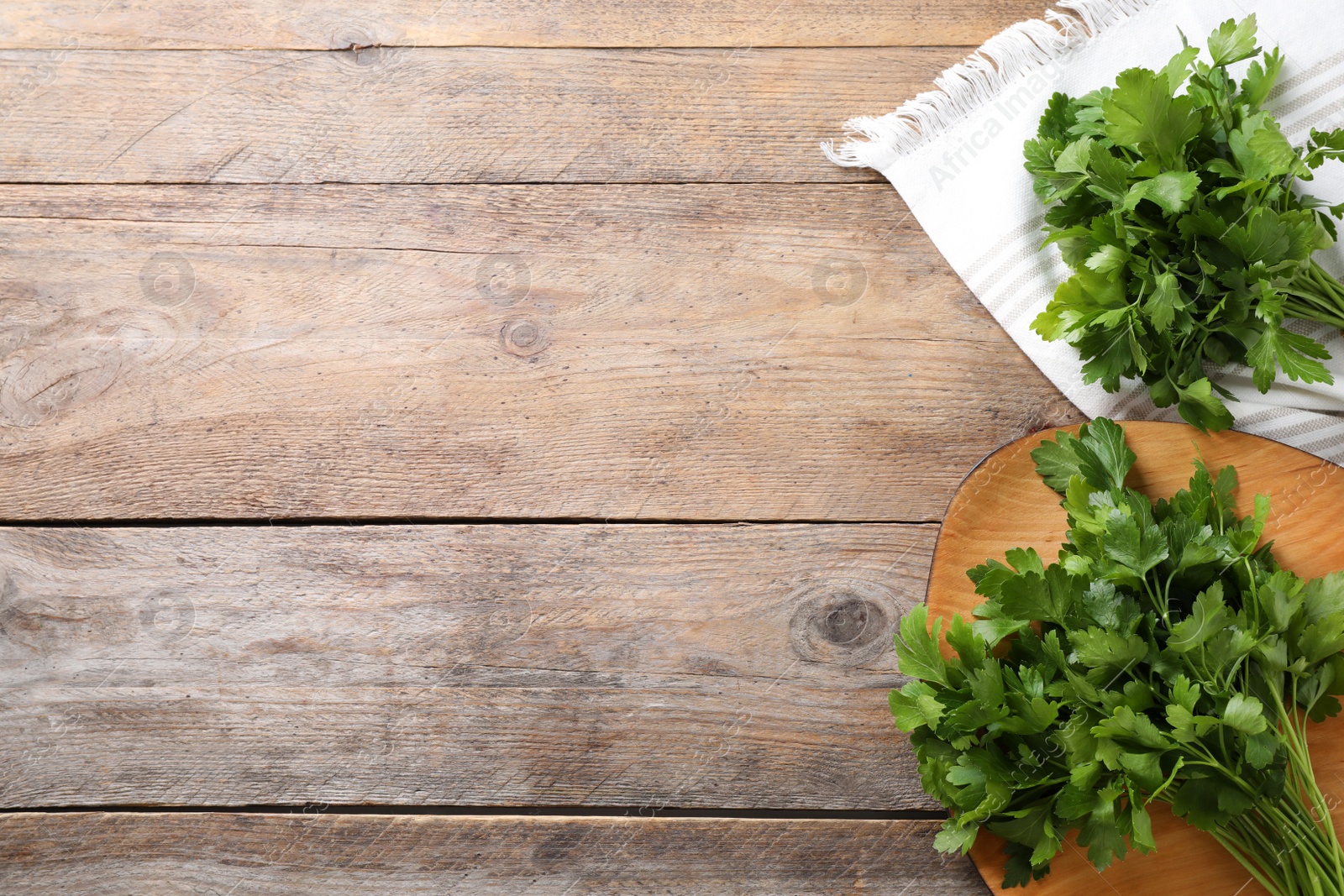 Photo of Bunch of fresh green parsley on wooden table, flat lay. Space for text