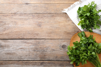 Bunch of fresh green parsley on wooden table, flat lay. Space for text