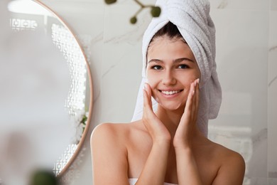 Photo of Beautiful teenage girl applying cleansing foam onto face in bathroom. Skin care cosmetic