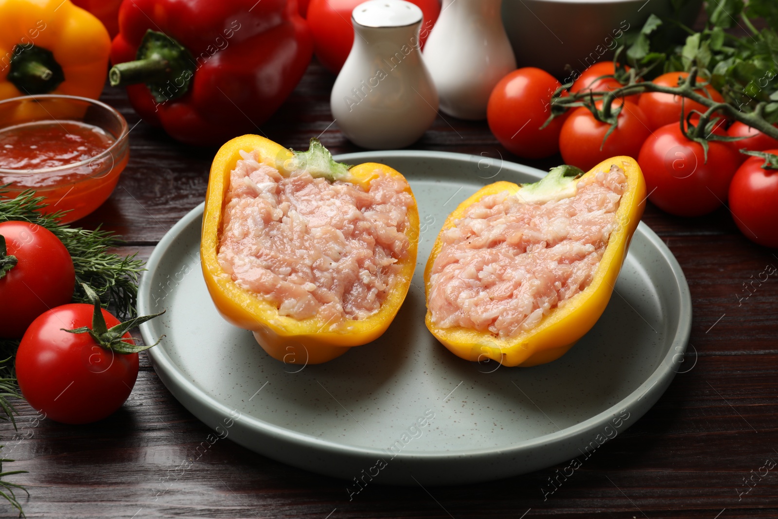 Photo of Raw stuffed peppers with ground meat and ingredients on wooden table