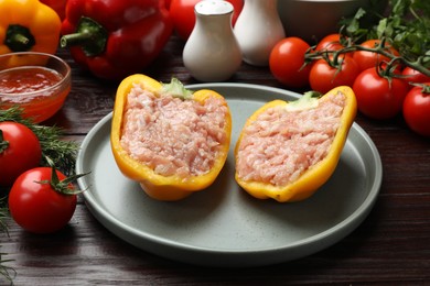 Photo of Raw stuffed peppers with ground meat and ingredients on wooden table