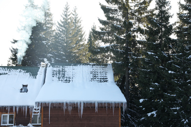 Wooden house covered with snow near forest. Winter vacation