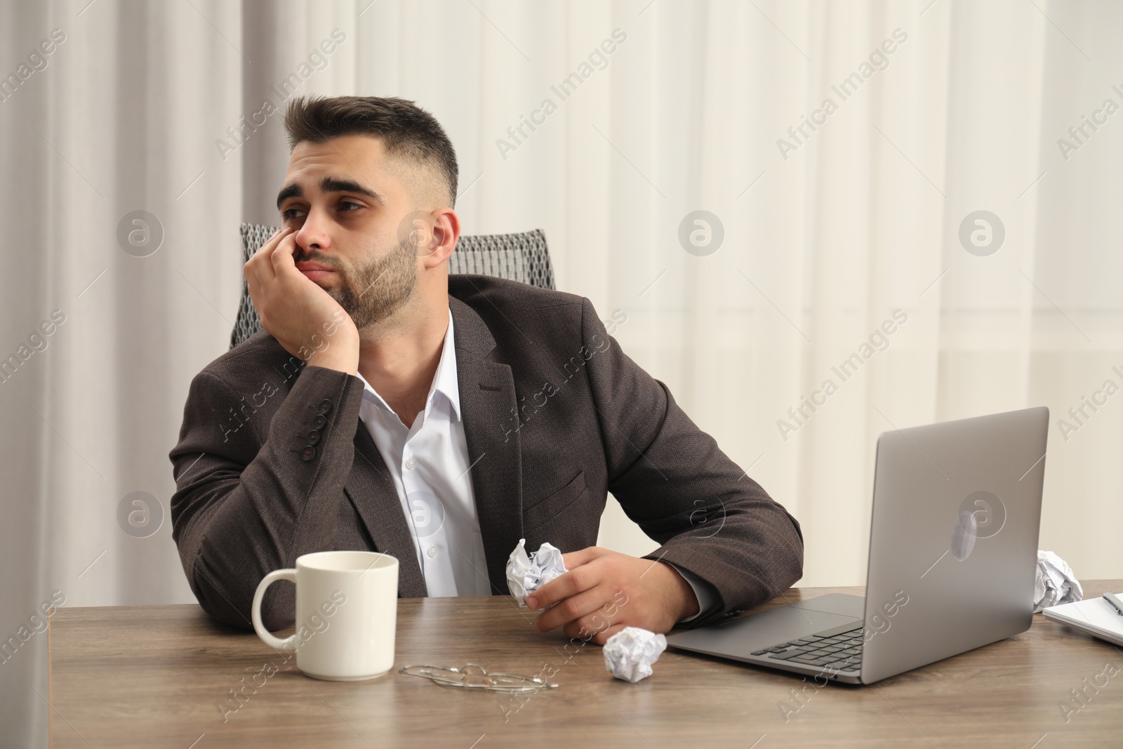 Photo of Sad businessman sitting at table in office