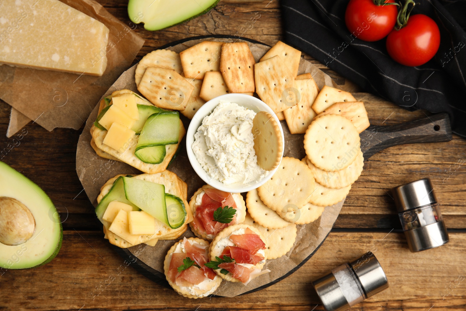 Photo of Different snacks with salted crackers on wooden table, flat lay