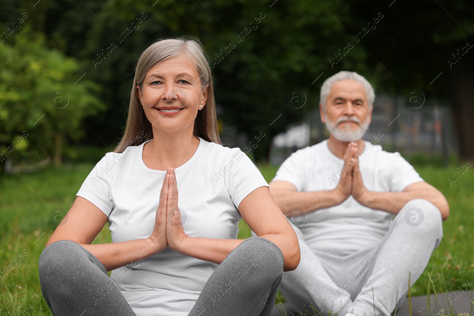 Photo of Senior couple practicing yoga in park, selective focus